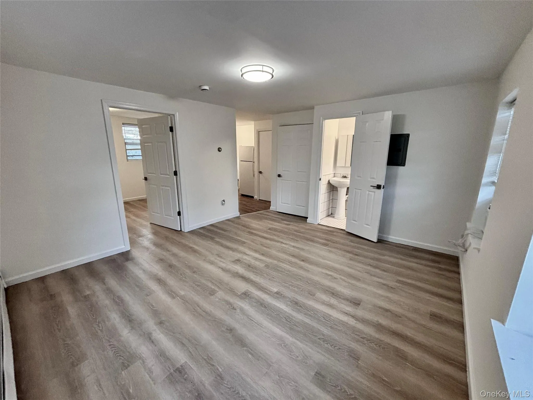 Unfurnished bedroom with baseboards, wood finished floors, a sink, and ensuite bath Unfurnished bedroom with baseboards, wood finished floors, a sink, and ensuite bath