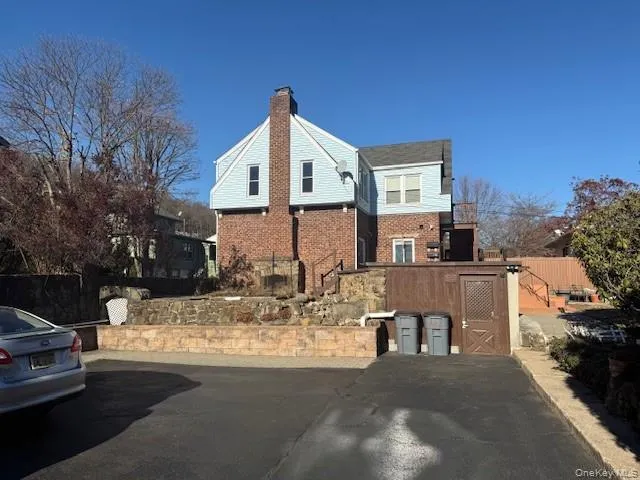 View of property exterior and driveway parking with a chimney and brick siding View of property exterior and driveway parking with a chimney and brick siding