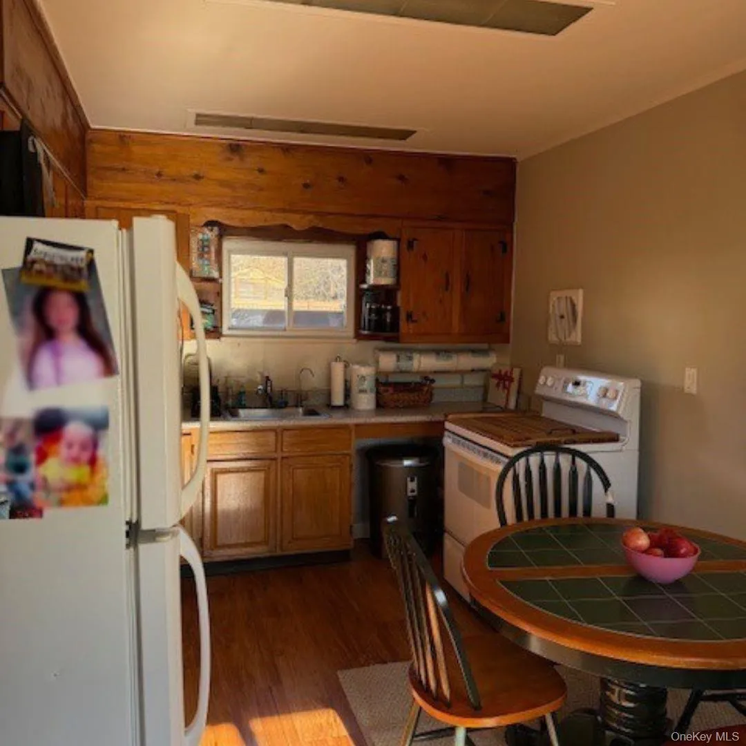 Kitchen featuring white appliances, light countertops, dark wood-style flooring, brown cabinets, and open shelves Kitchen featuring white appliances, light countertops, dark wood-style flooring, brown cabinets, and open shelves