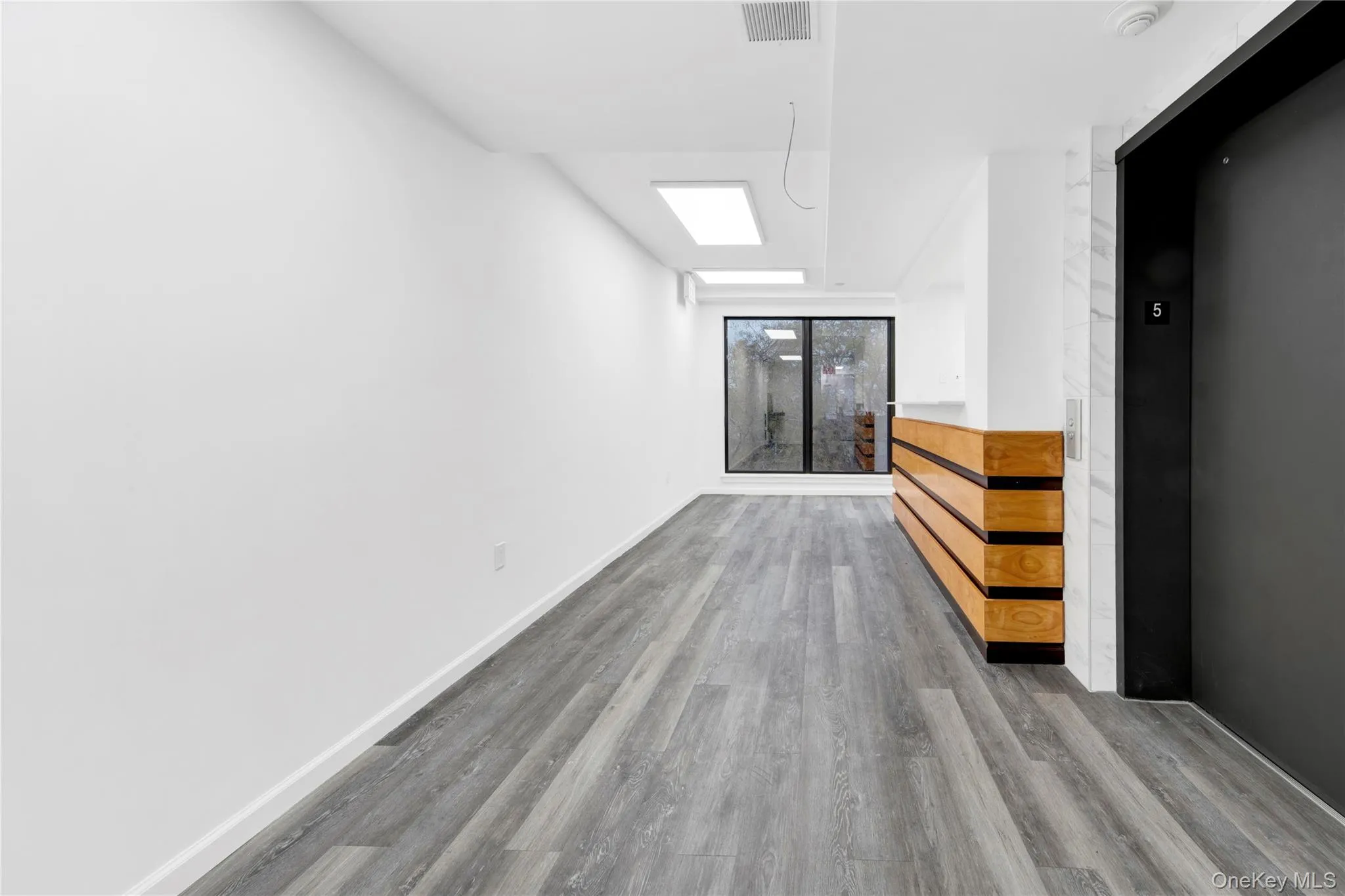 Spare room featuring a skylight, elevator, and wood finished floors Spare room featuring a skylight, elevator, and wood finished floors