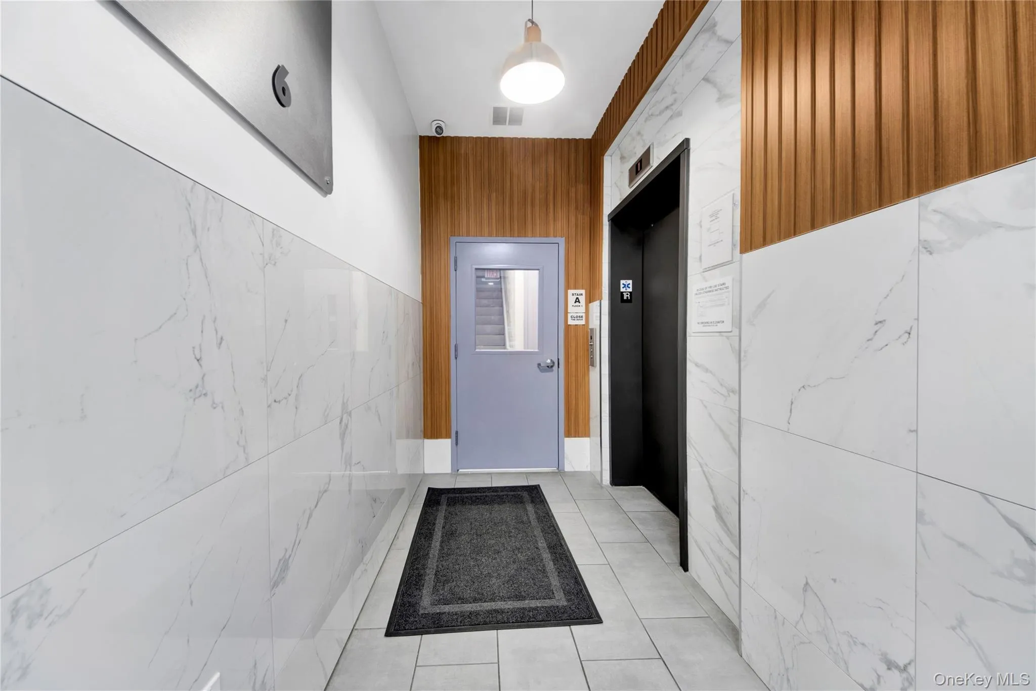 Entryway with elevator, tile patterned floors, and tile walls Entryway with elevator, tile patterned floors, and tile walls