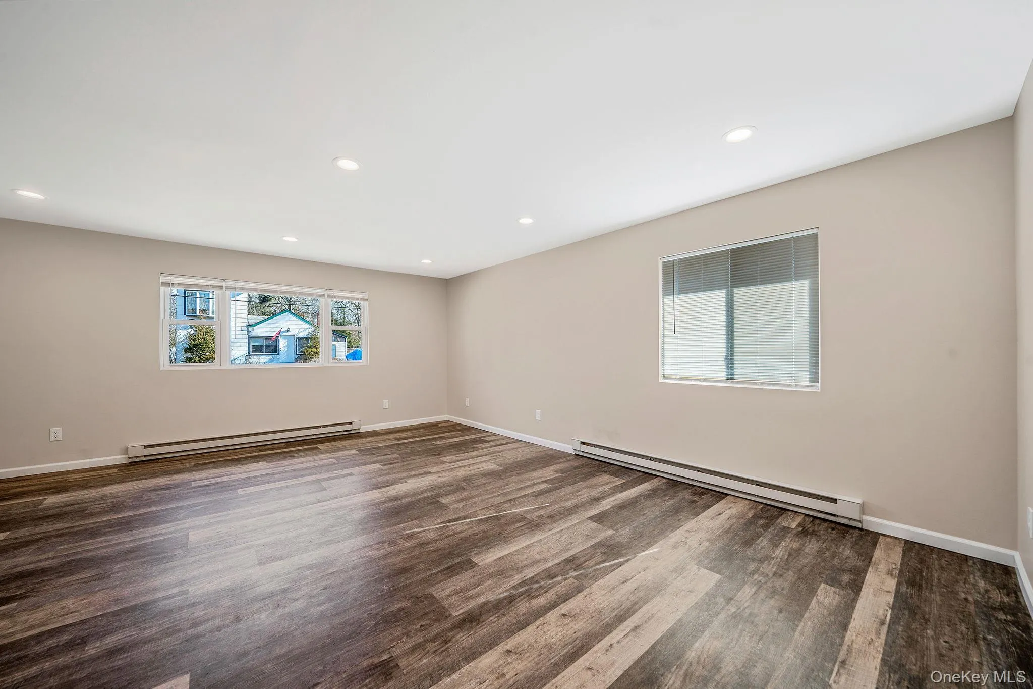 Empty room with a baseboard heating unit, dark wood finished floors, and recessed lighting Empty room with a baseboard heating unit, dark wood finished floors, and recessed lighting