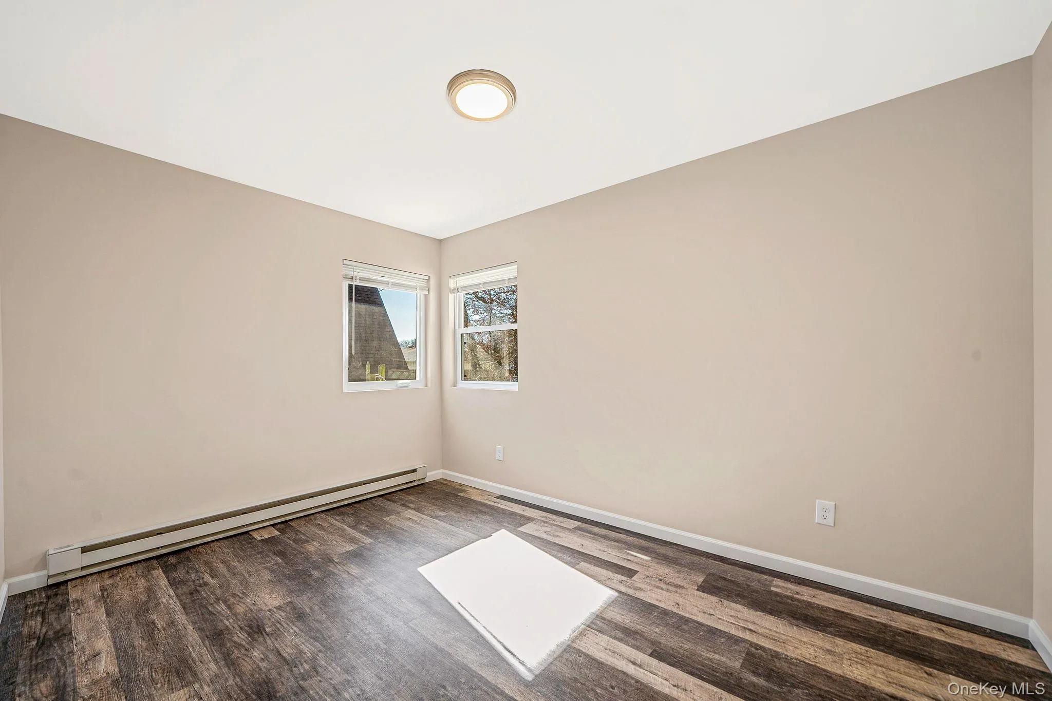 Spare room featuring baseboard heating and dark wood finished floors Spare room featuring baseboard heating and dark wood finished floors