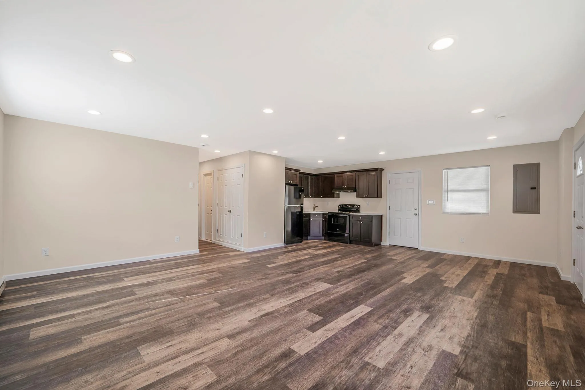 Unfurnished living room featuring electric panel, recessed lighting, and dark wood-type flooring Unfurnished living room featuring electric panel, recessed lighting, and dark wood-type flooring