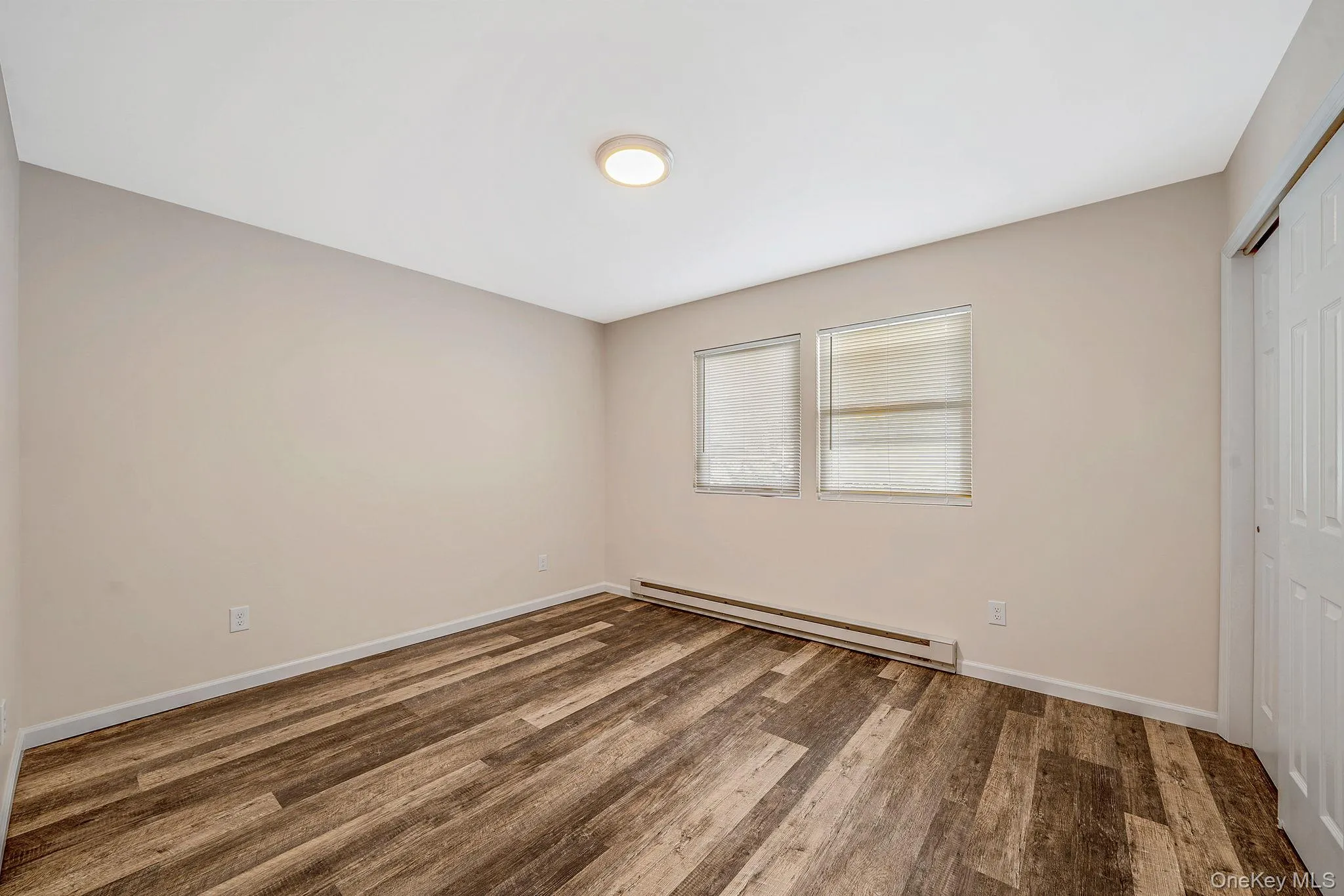 Unfurnished bedroom featuring a closet, a baseboard radiator, and wood finished floors Unfurnished bedroom featuring a closet, a baseboard radiator, and wood finished floors