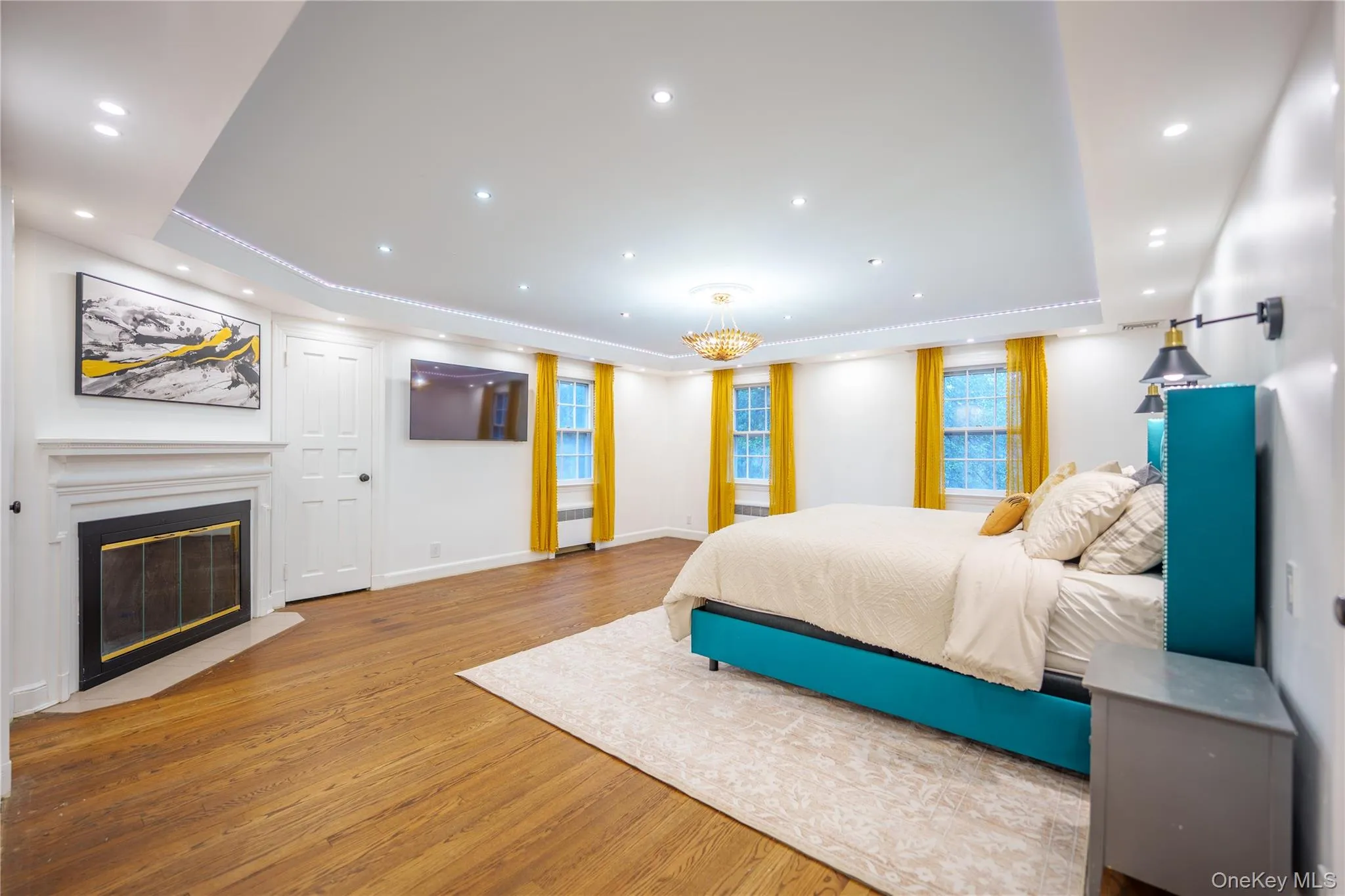 Primary Bedroom has 4th of 5 fireplaces. New recessed lighting, a tray ceiling, a glass covered fireplace, and original wood floors plus 2 closets Primary Bedroom has 4th of 5 fireplaces. New recessed lighting, a tray ceiling, a glass covered fireplace, and original wood floors plus 2 closets