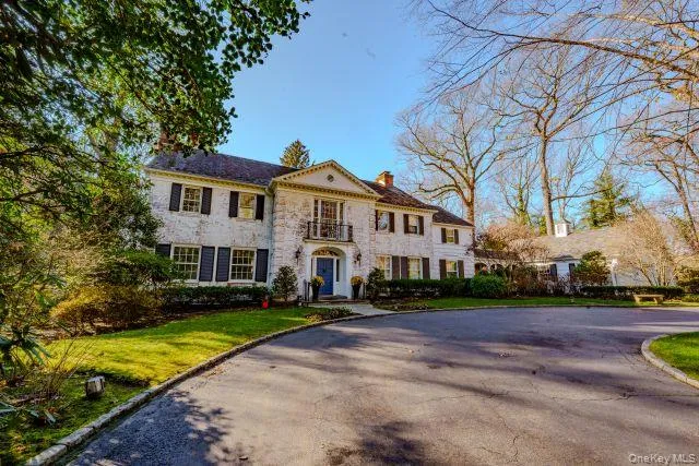 View of front of house with a chimney, driveway, a front lawn, and a balcony View of front of house with a chimney, driveway, a front lawn, and a balcony