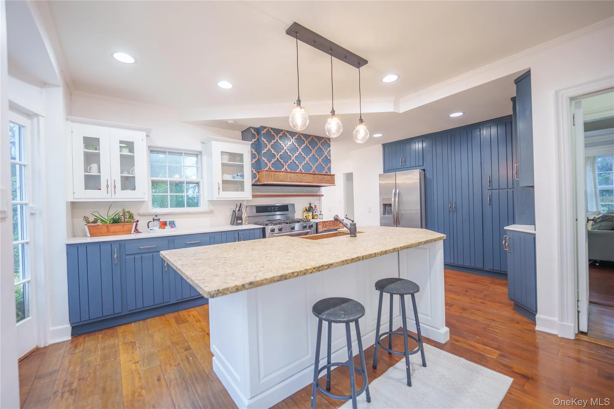 Kitchen with blue cabinetry, white cabinetry, glass insert cabinets, decorative light fixtures, and a breakfast bar Kitchen with blue cabinetry, white cabinetry, glass insert cabinets, decorative light fixtures, and a breakfast bar