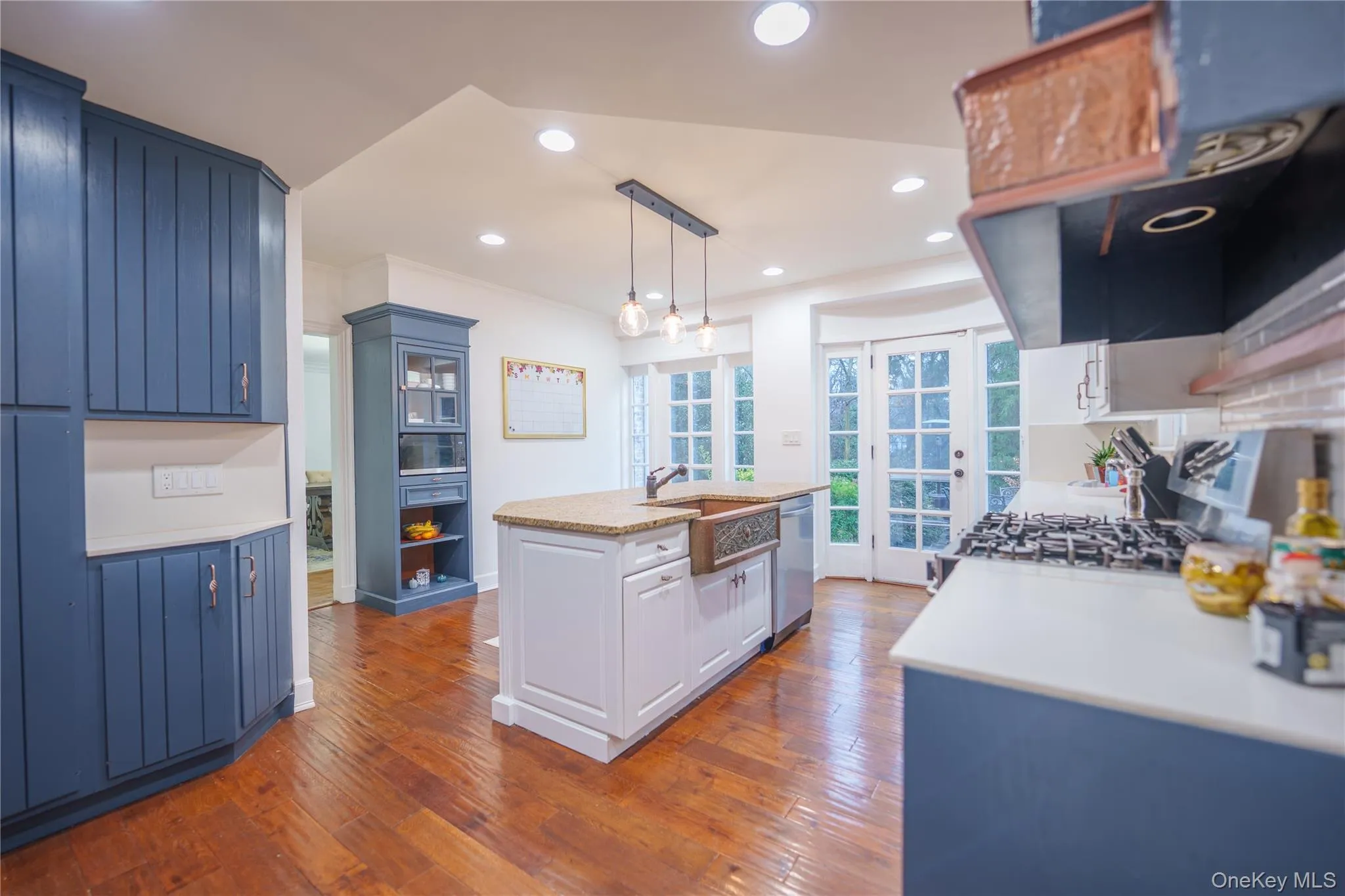 Kitchen featuring pendant light fixtures over breakfast bar, blue cabinets, a center island with sink, recessed lighting, and range with gas cooktop Kitchen featuring pendant light fixtures over breakfast bar, blue cabinets, a center island with sink, recessed lighting, and range with gas cooktop