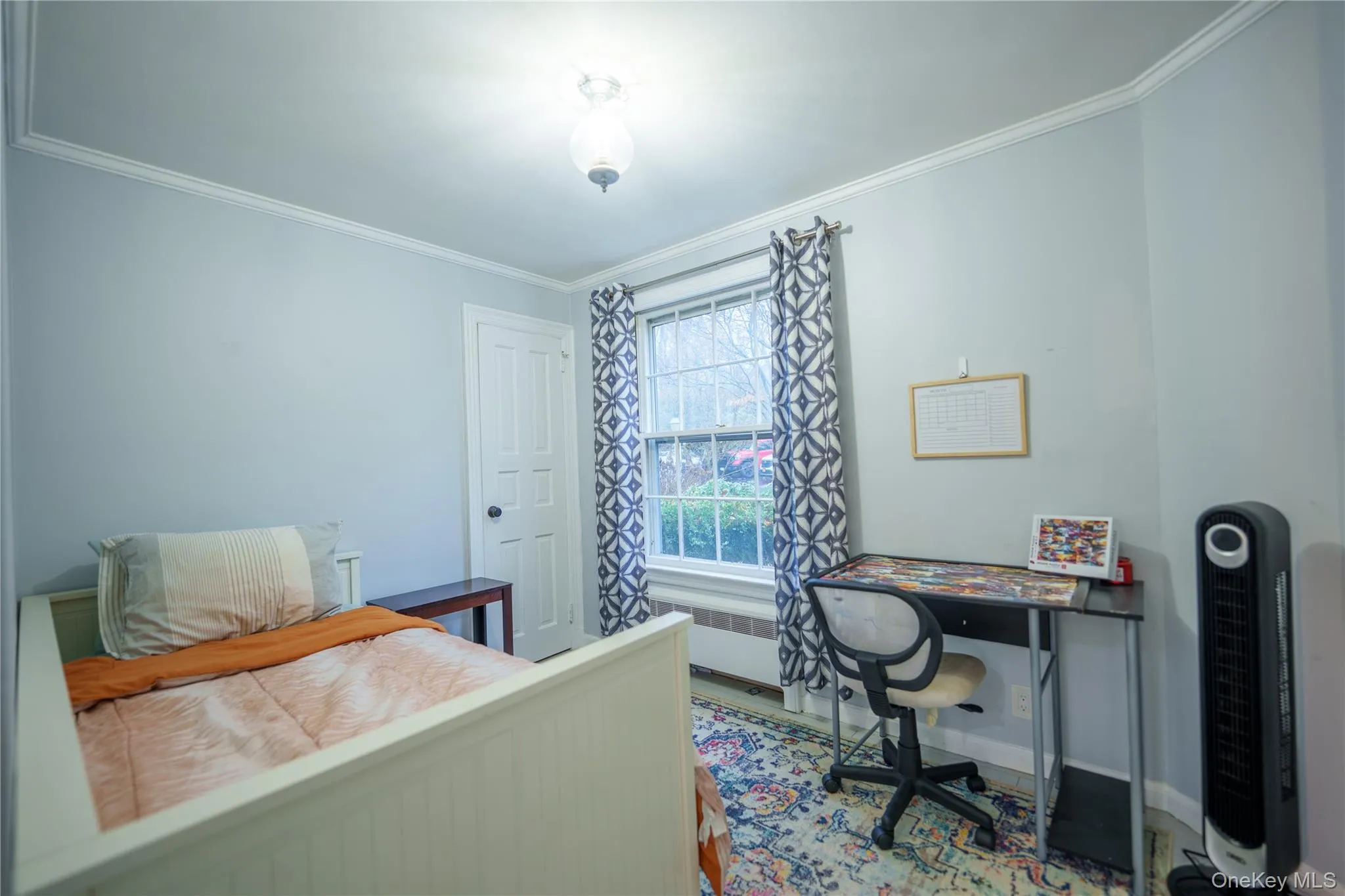 Bedroom with crown molding, radiator heating unit, and an office area Bedroom with crown molding, radiator heating unit, and an office area