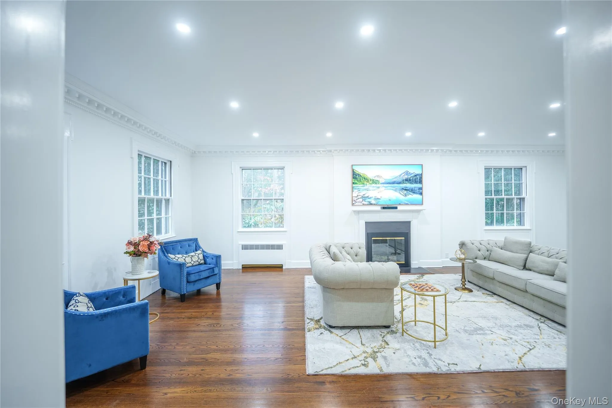 Formal living room with glass first of 5 fireplaces, original dentil moldings, hardwood floors, and recessed lighting Formal living room with glass first of 5 fireplaces, original dentil moldings, hardwood floors, and recessed lighting