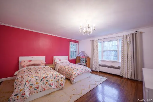 Oversized bedroom with a chandelier, crown molding, dark wood flooring, and jack and jill bath entrance Oversized bedroom with a chandelier, crown molding, dark wood flooring, and jack and jill bath entrance