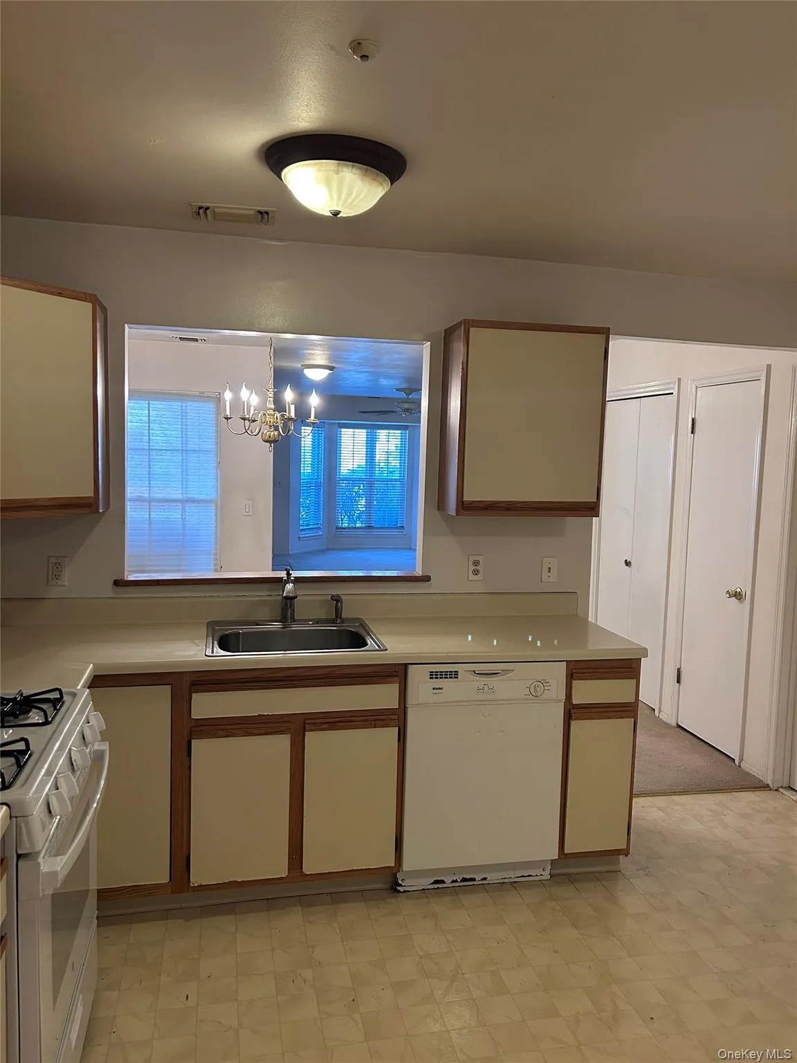 Kitchen featuring white appliances, light floors, light countertops, and a chandelier Kitchen featuring white appliances, light floors, light countertops, and a chandelier