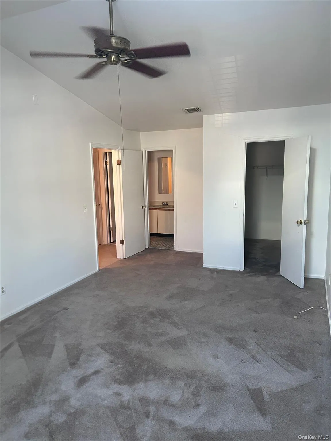 Unfurnished bedroom featuring carpet flooring, ensuite bath, a ceiling fan, a spacious closet, and lofted ceiling Unfurnished bedroom featuring carpet flooring, ensuite bath, a ceiling fan, a spacious closet, and lofted ceiling