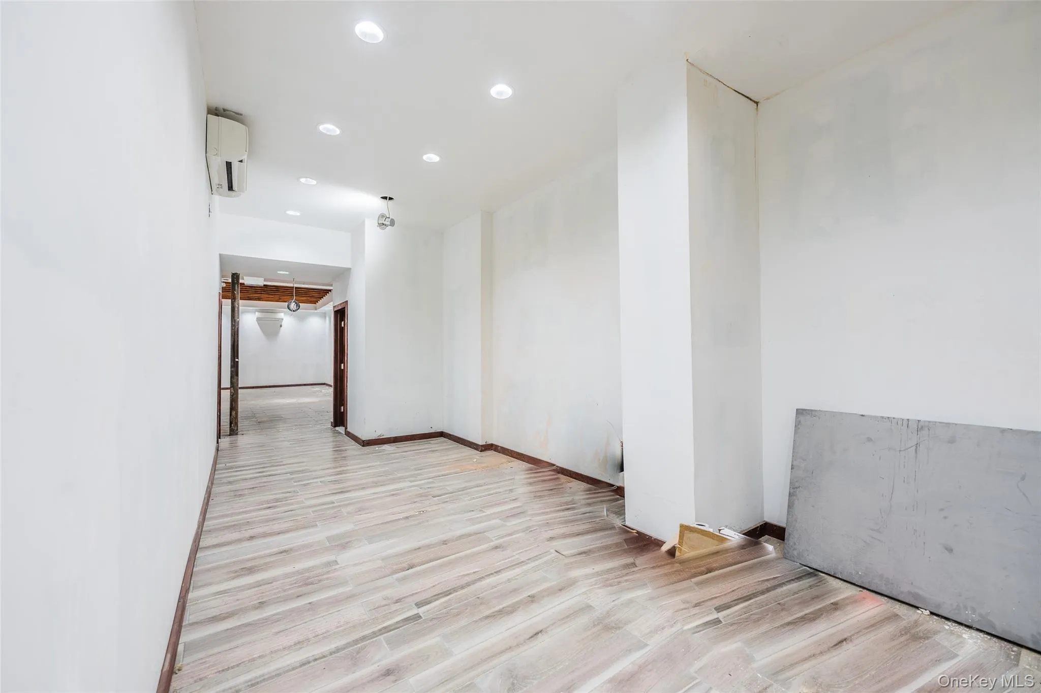 Empty room with recessed lighting, light wood-style flooring, and a wall mounted air conditioner Empty room with recessed lighting, light wood-style flooring, and a wall mounted air conditioner