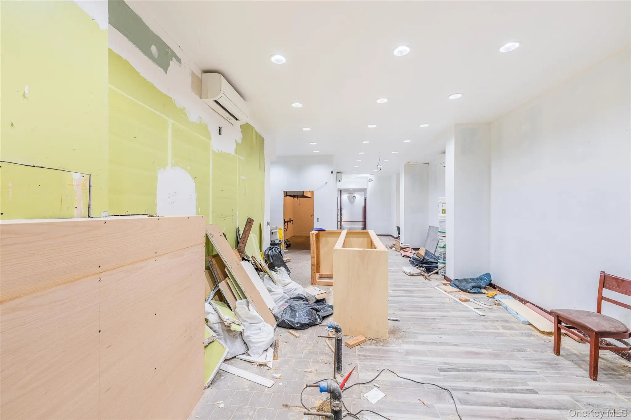 Hallway featuring recessed lighting, a wall mounted AC, and light wood-style flooring Hallway featuring recessed lighting, a wall mounted AC, and light wood-style flooring