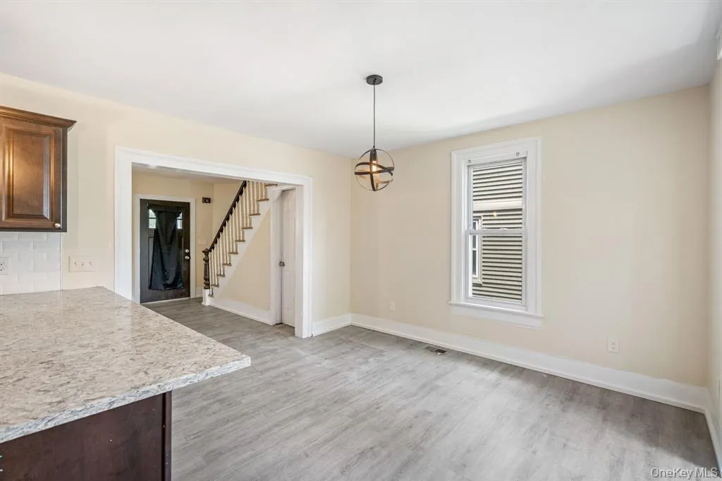 Unfurnished dining area featuring stairs and light wood-style flooring Unfurnished dining area featuring stairs and light wood-style flooring