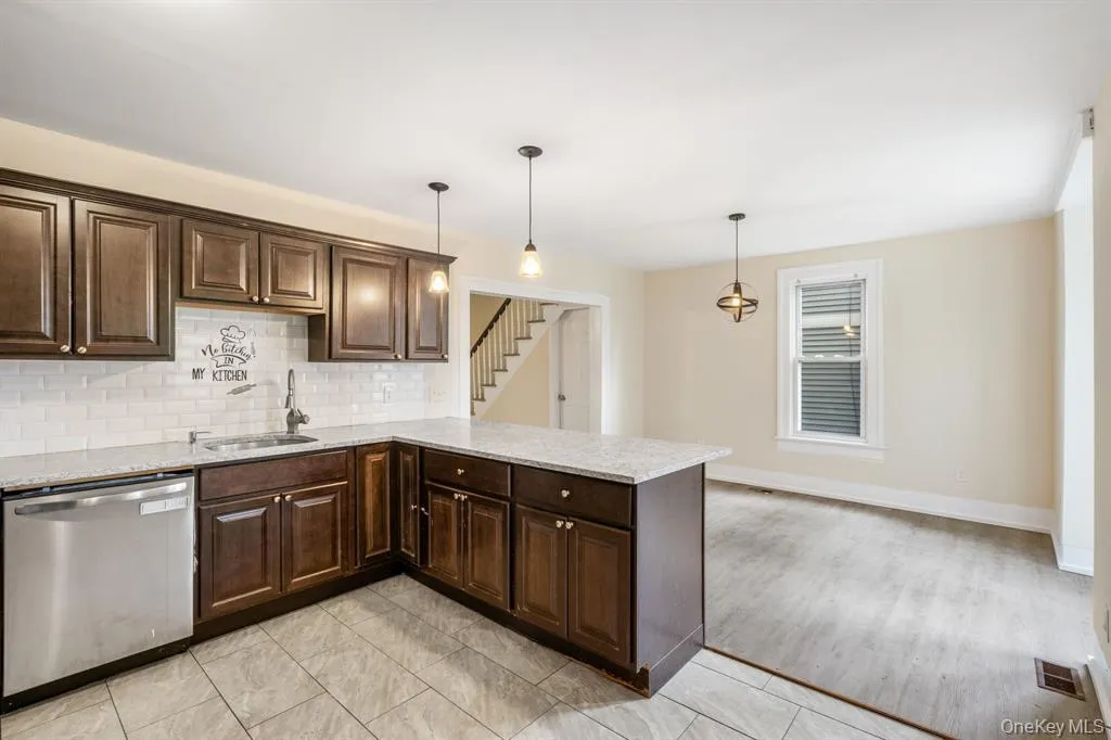Kitchen with dark brown cabinets, dishwasher, light stone countertops, and a peninsula Kitchen with dark brown cabinets, dishwasher, light stone countertops, and a peninsula