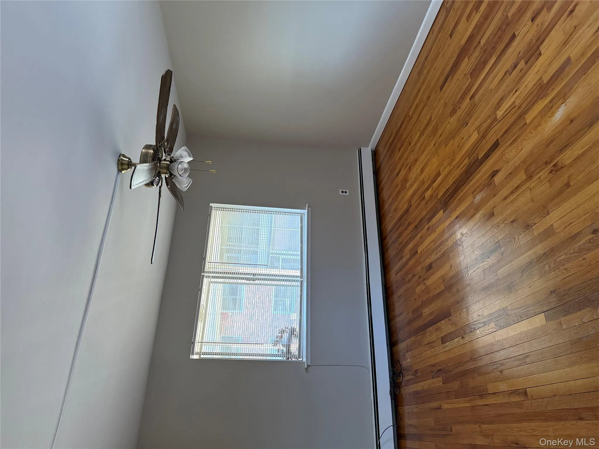 Spare room featuring hardwood / wood-style flooring, a baseboard radiator, and a ceiling fan Spare room featuring hardwood / wood-style flooring, a baseboard radiator, and a ceiling fan