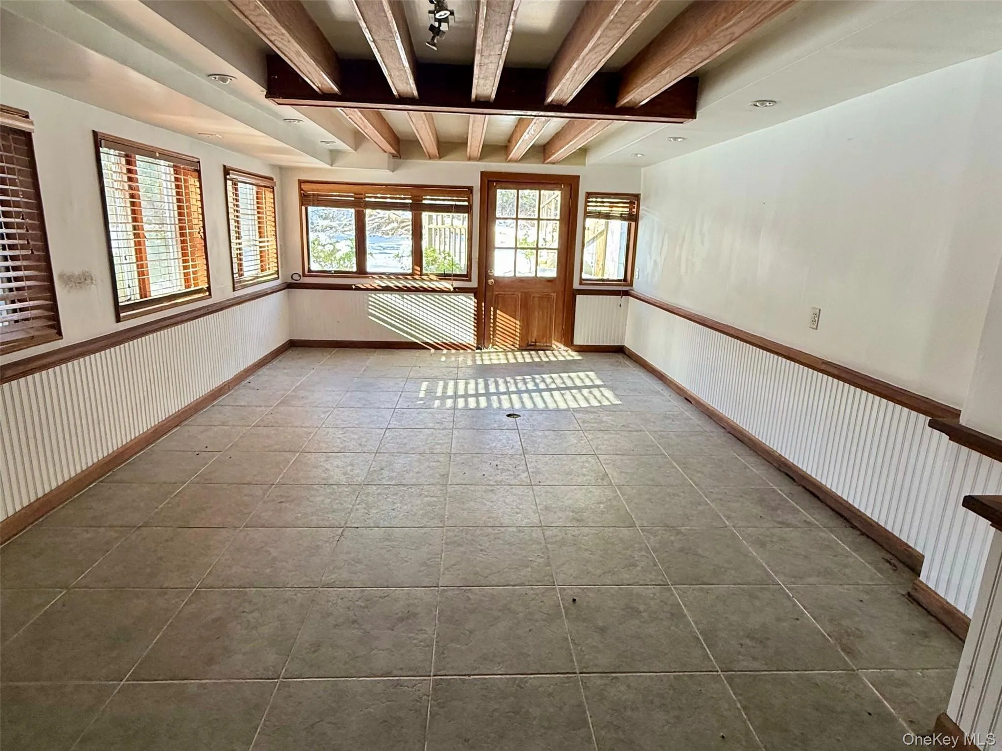 Empty room featuring beam ceiling and tile patterned flooring Empty room featuring beam ceiling and tile patterned flooring