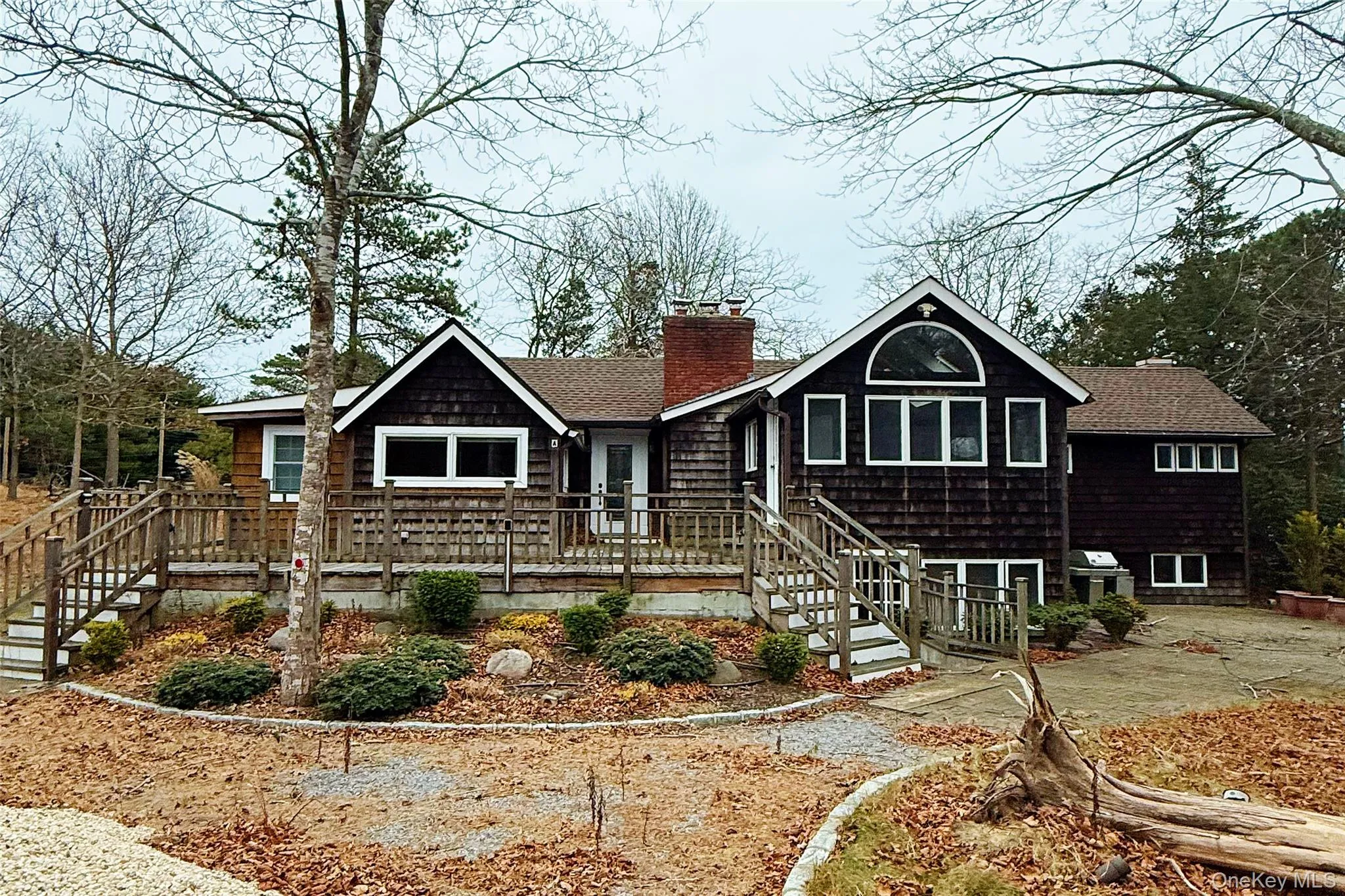 View of front of property featuring stairway, a chimney, and a wooden deck View of front of property featuring stairway, a chimney, and a wooden deck