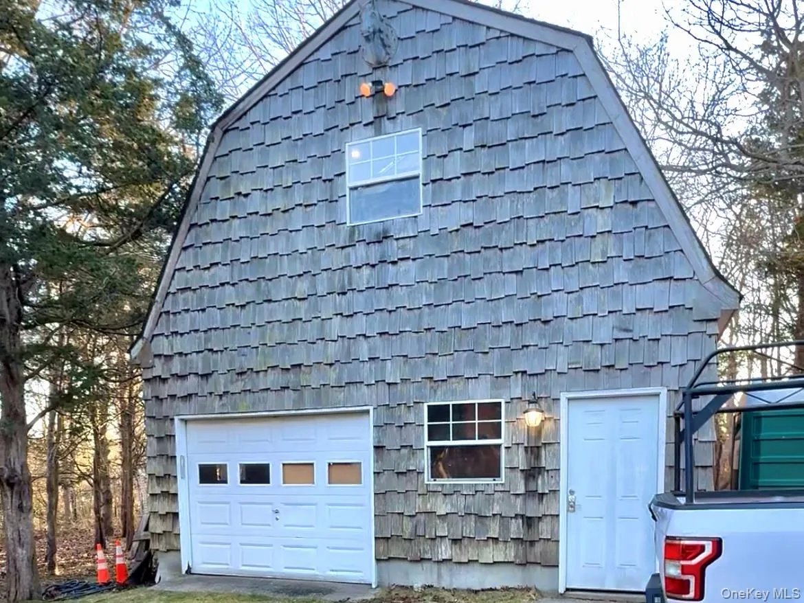 View of front of house featuring a gambrel roof and a garage View of front of house featuring a gambrel roof and a garage