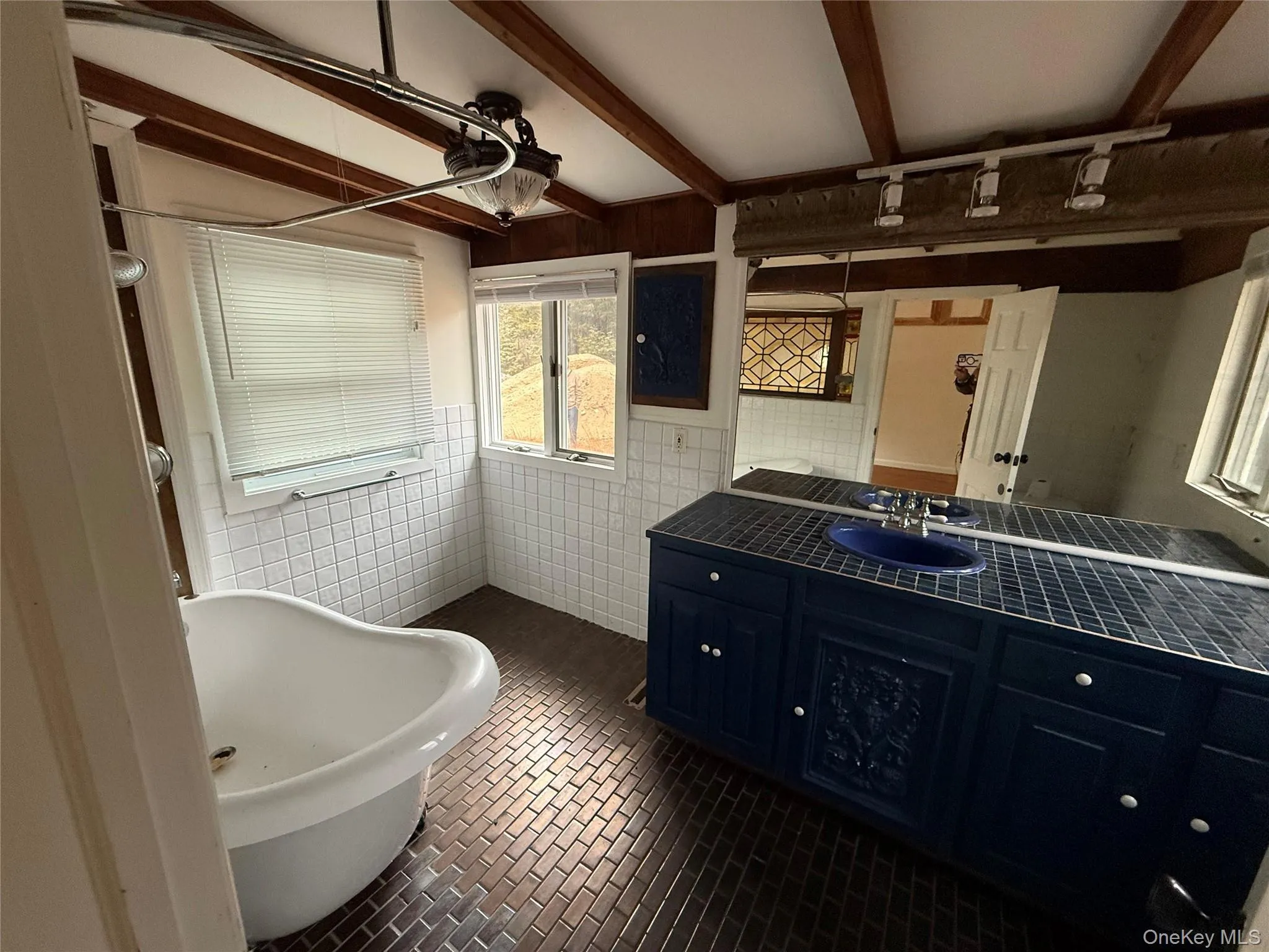 Bathroom with tile walls, a freestanding bath, vanity, and beamed ceiling Bathroom with tile walls, a freestanding bath, vanity, and beamed ceiling