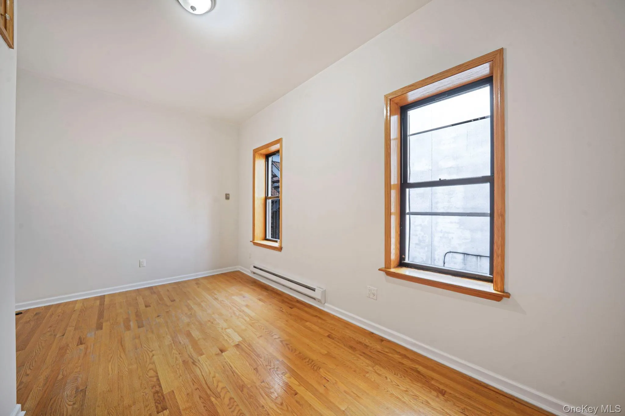 Unfurnished room with a baseboard heating unit and wood finished floors Unfurnished room with a baseboard heating unit and wood finished floors