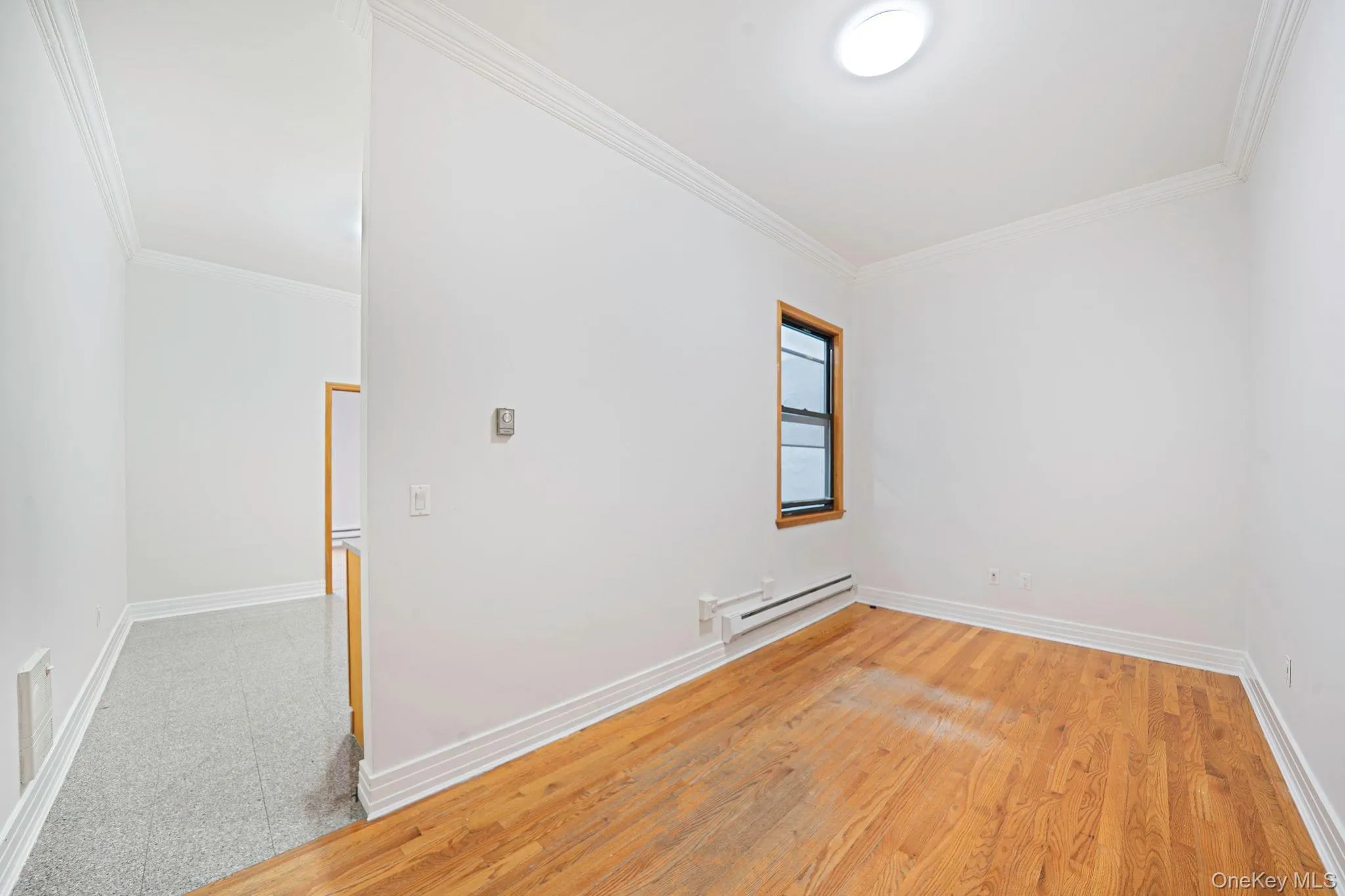 Unfurnished room with light wood-style flooring, a baseboard radiator, and crown molding Unfurnished room with light wood-style flooring, a baseboard radiator, and crown molding