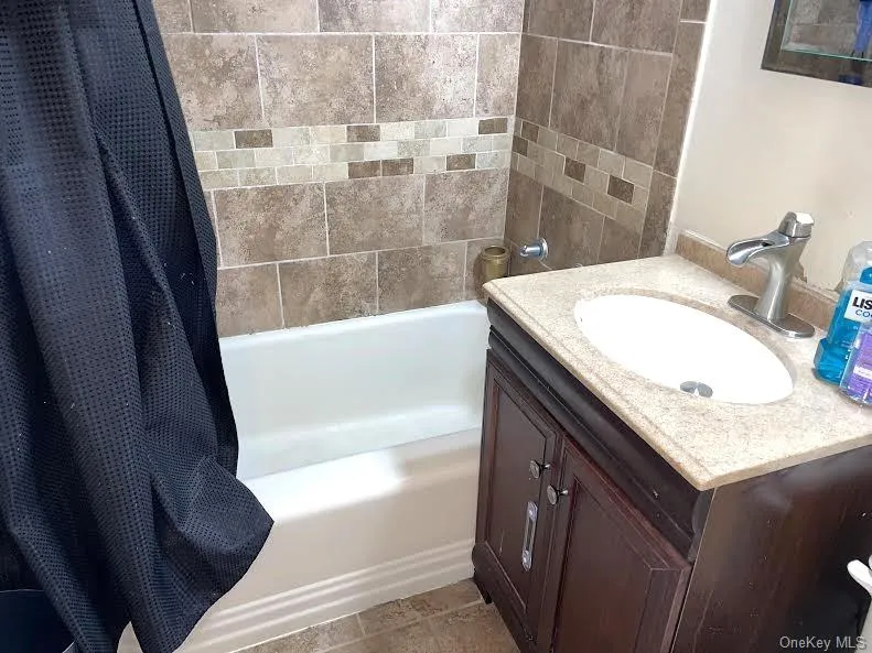 Bathroom with tile patterned flooring, vanity, and shower / bath combination with curtain Bathroom with tile patterned flooring, vanity, and shower / bath combination with curtain