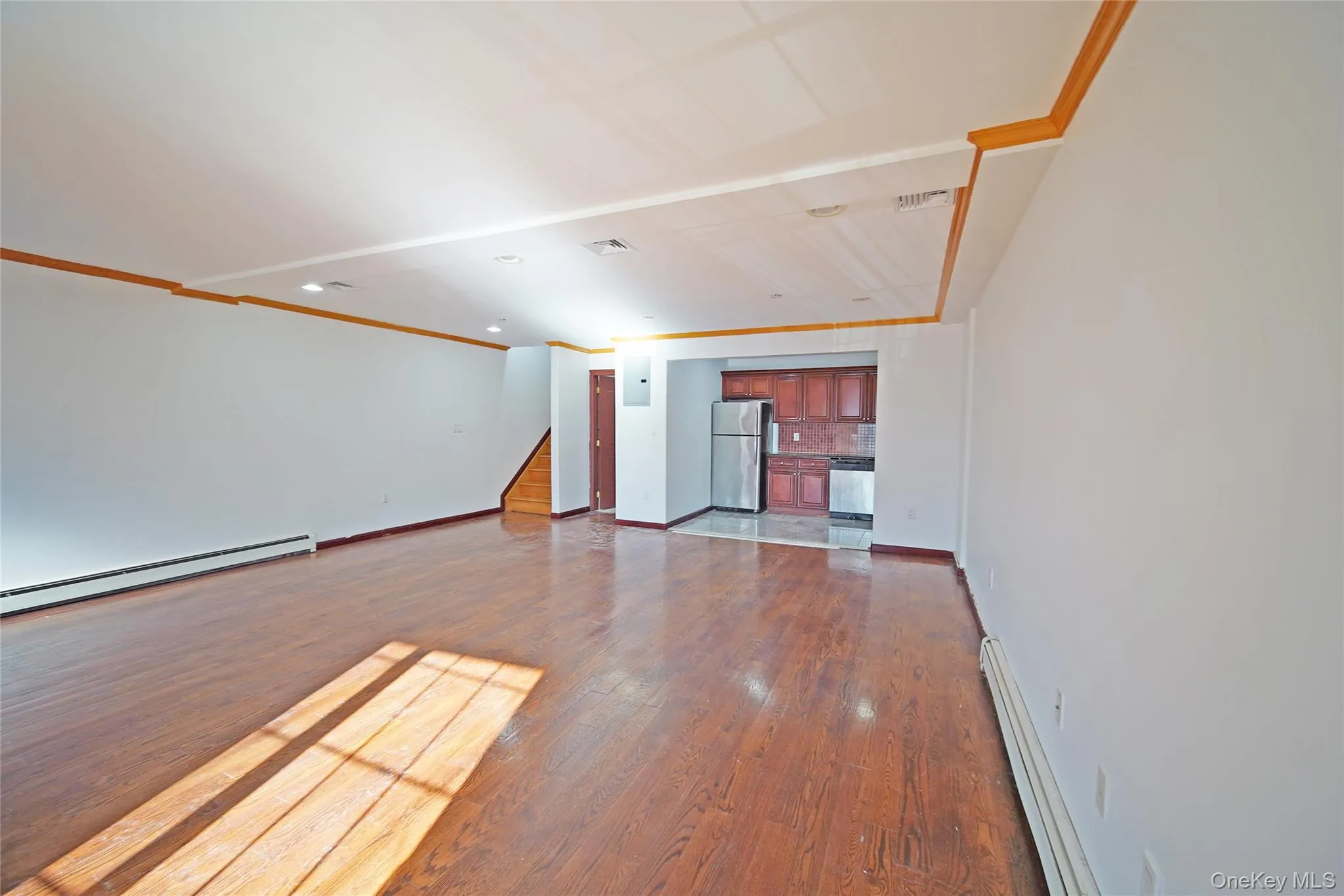 Unfurnished living room featuring a baseboard heating unit, a baseboard radiator, dark wood-type flooring, crown molding, and recessed lighting Unfurnished living room featuring a baseboard heating unit, a baseboard radiator, dark wood-type flooring, crown molding, and recessed lighting