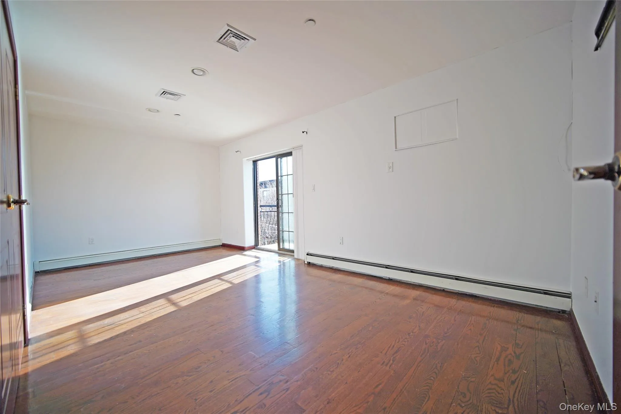 Empty room featuring baseboard heating, hardwood / wood-style flooring, and recessed lighting Empty room featuring baseboard heating, hardwood / wood-style flooring, and recessed lighting