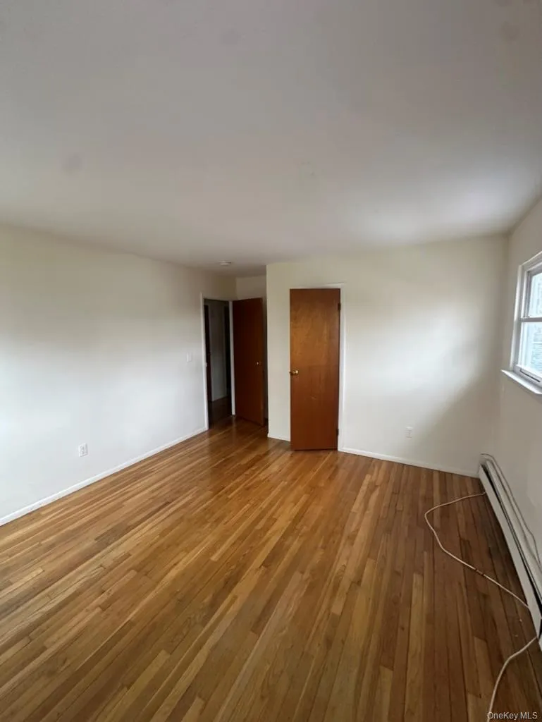 second bedroom with hardwood / wood-style floors and a baseboard radiator second bedroom with hardwood / wood-style floors and a baseboard radiator