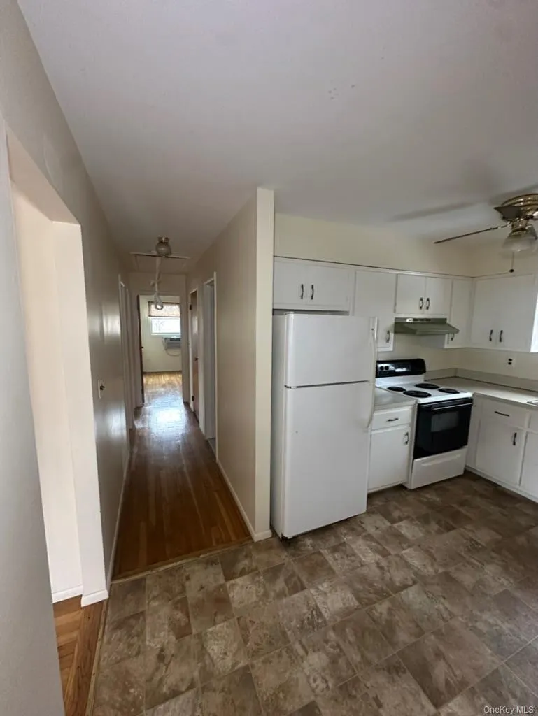 Kitchen featuring white cabinets, ceiling fan, and white appliances Kitchen featuring white cabinets, ceiling fan, and white appliances