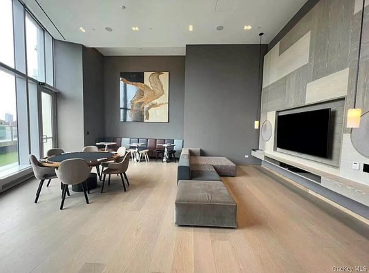 Living area featuring light wood-type flooring, an accent wall, and a towering ceiling Living area featuring light wood-type flooring, an accent wall, and a towering ceiling