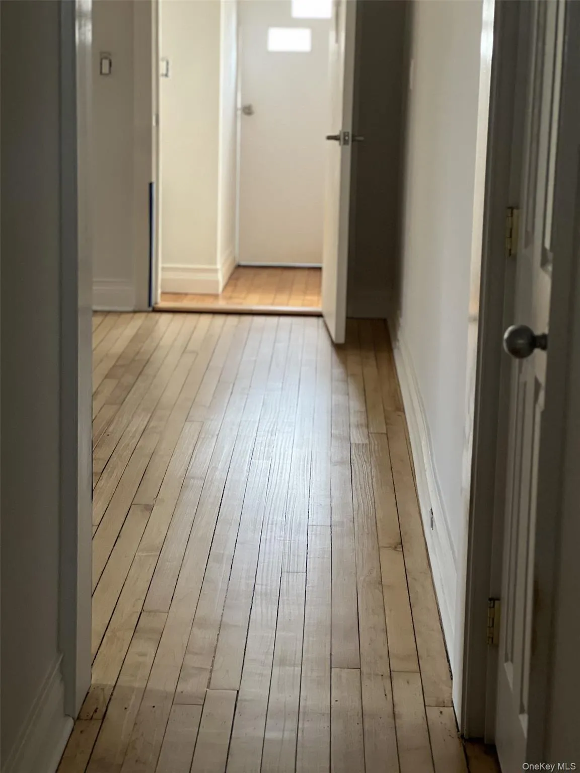 Hallway with light wood-type flooring and baseboards Hallway with light wood-type flooring and baseboards