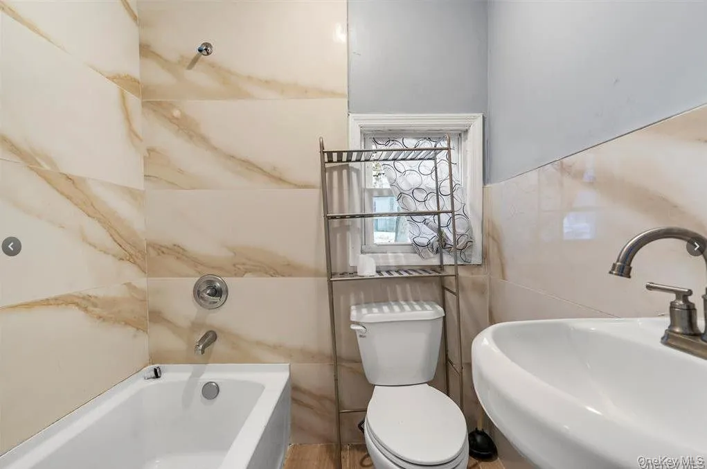 Full bath featuring a sink and tile walls Full bath featuring a sink and tile walls
