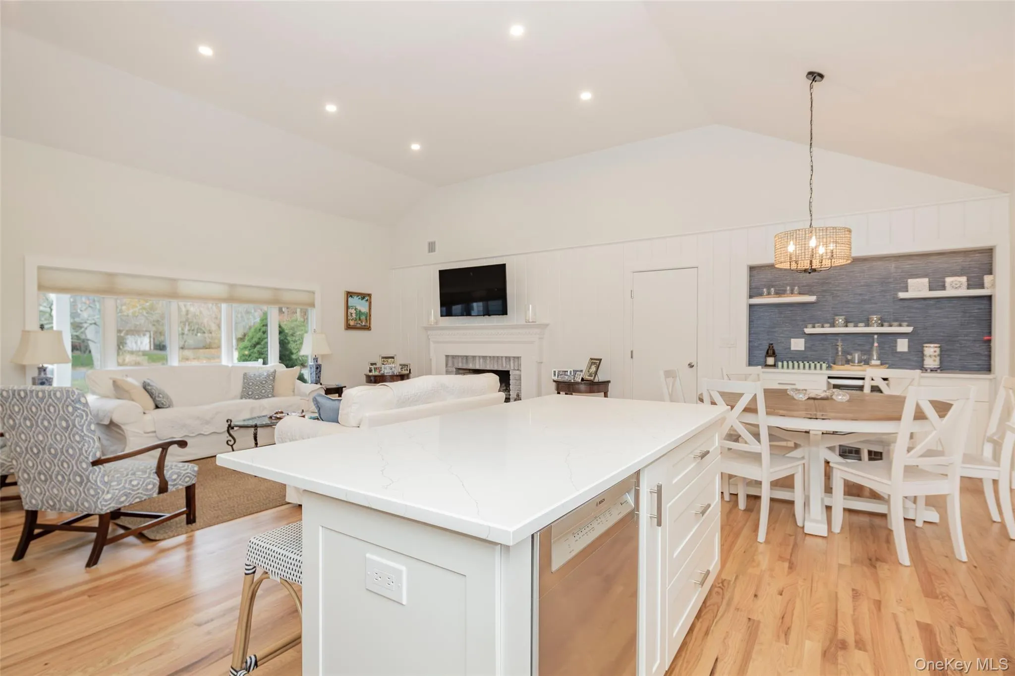 Kitchen with a kitchen breakfast bar, hanging light fixtures, a center island, lofted ceiling, and white cabinetry Kitchen with a kitchen breakfast bar, hanging light fixtures, a center island, lofted ceiling, and white cabinetry