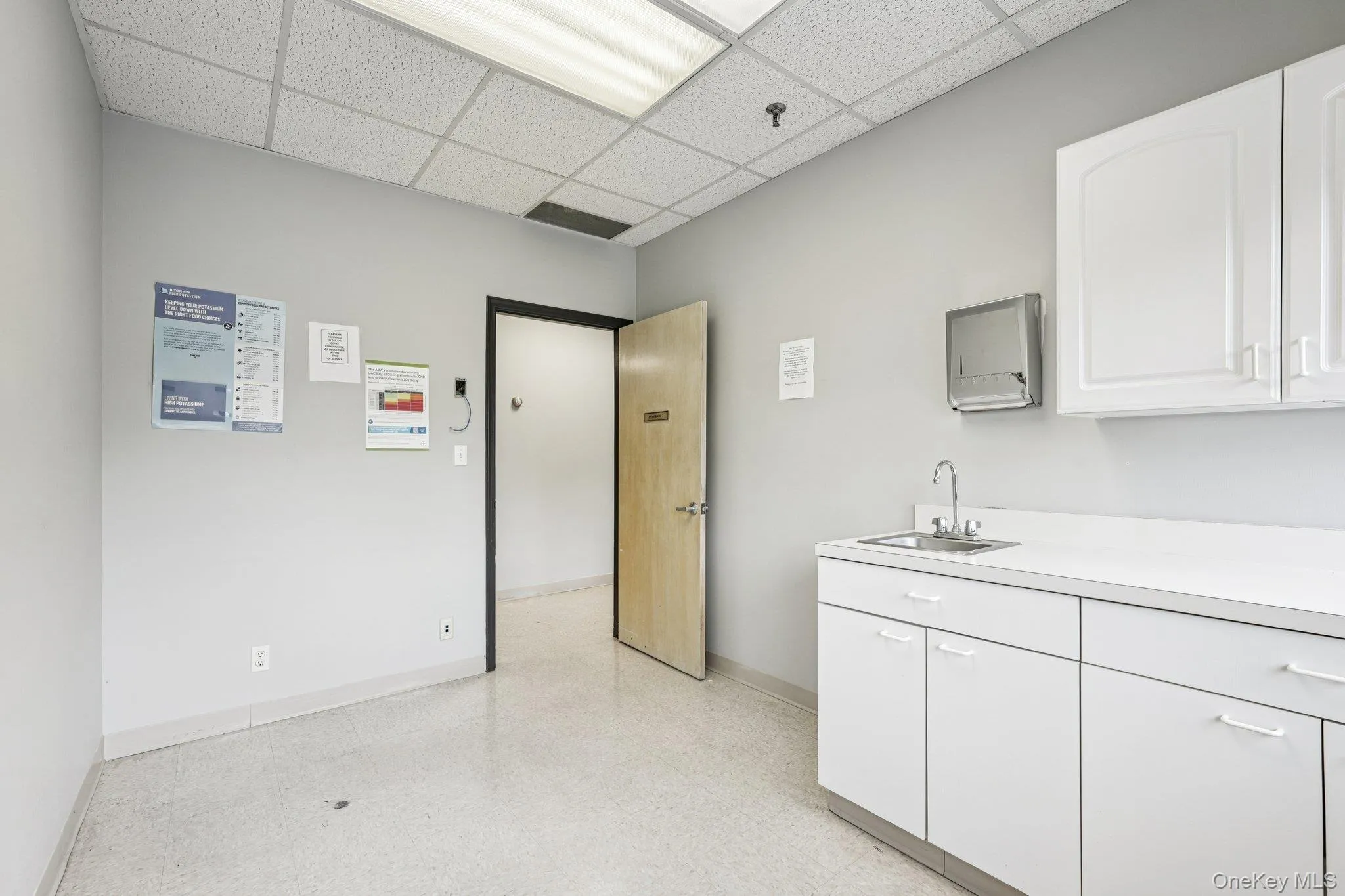 Kitchen featuring light countertops, white cabinetry, and a paneled ceiling Kitchen featuring light countertops, white cabinetry, and a paneled ceiling