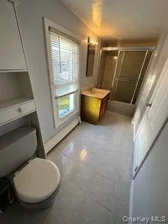 Bathroom with a shower with shower door, vanity, and light tile patterned floors Bathroom with a shower with shower door, vanity, and light tile patterned floors