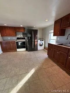 Kitchen with stainless steel stove, decorative backsplash, washer / clothes dryer, black refrigerator with ice dispenser, and recessed lighting Kitchen with stainless steel stove, decorative backsplash, washer / clothes dryer, black refrigerator with ice dispenser, and recessed lighting