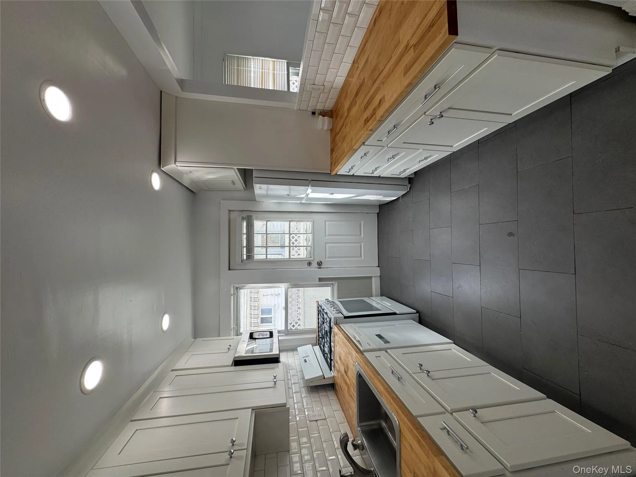 Kitchen with butcher block counters, tasteful backsplash, white cabinets, stove, and recessed lighting Kitchen with butcher block counters, tasteful backsplash, white cabinets, stove, and recessed lighting