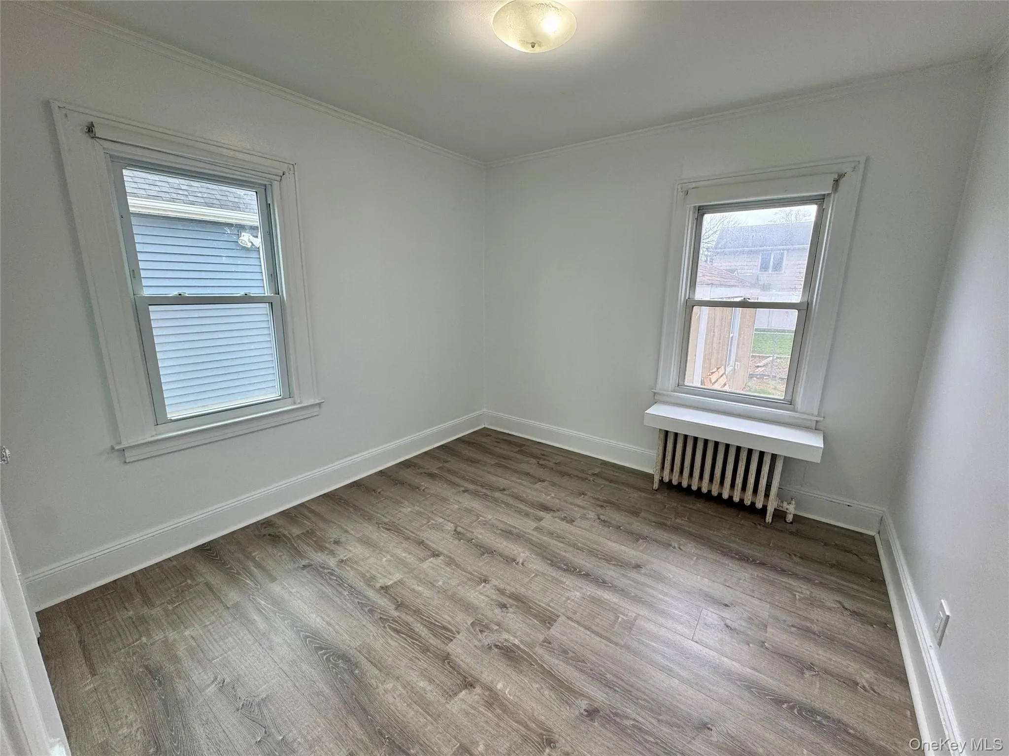 Spare room with light wood-style flooring, radiator heating unit, and ornamental molding Spare room with light wood-style flooring, radiator heating unit, and ornamental molding