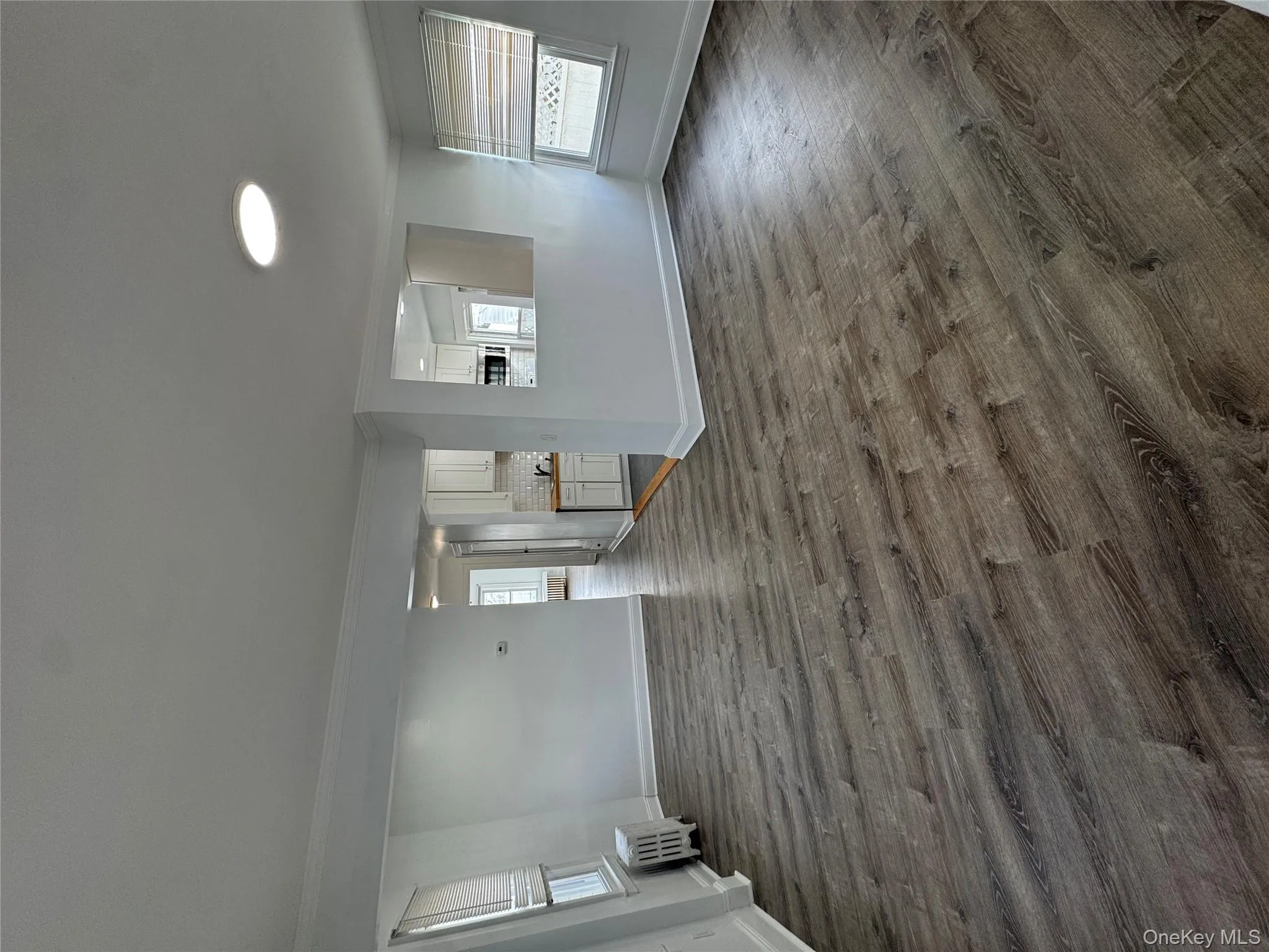 Unfurnished living room featuring radiator heating unit, ornamental molding, and dark wood-style floors Unfurnished living room featuring radiator heating unit, ornamental molding, and dark wood-style floors