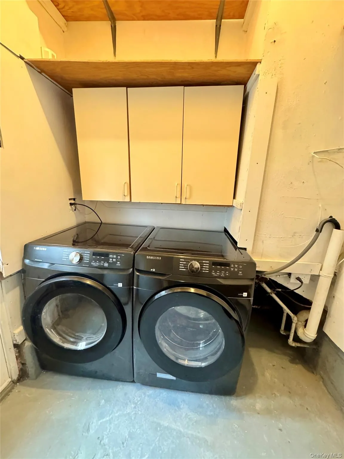 Laundry room featuring unfinished concrete flooring, separate washer and dryer, and cabinet space Laundry room featuring unfinished concrete flooring, separate washer and dryer, and cabinet space