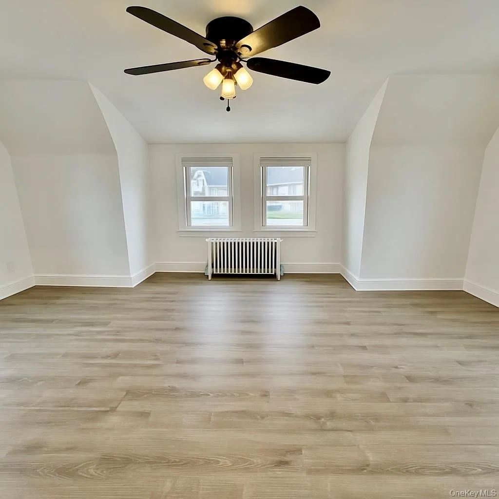 Bedroom featuring lofted ceiling, radiator heating unit, and light wood-style flooring Bedroom featuring lofted ceiling, radiator heating unit, and light wood-style flooring