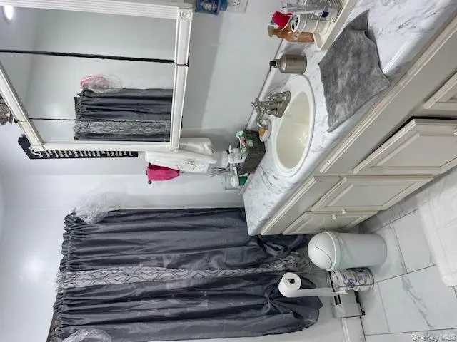 Bathroom featuring vanity, a shower with shower curtain, and a baseboard radiator Bathroom featuring vanity, a shower with shower curtain, and a baseboard radiator