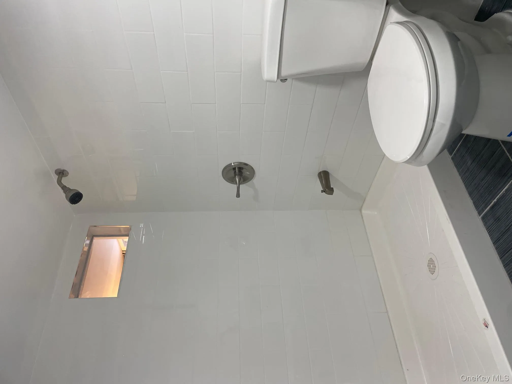 Bathroom featuring toilet and tiled shower Bathroom featuring toilet and tiled shower