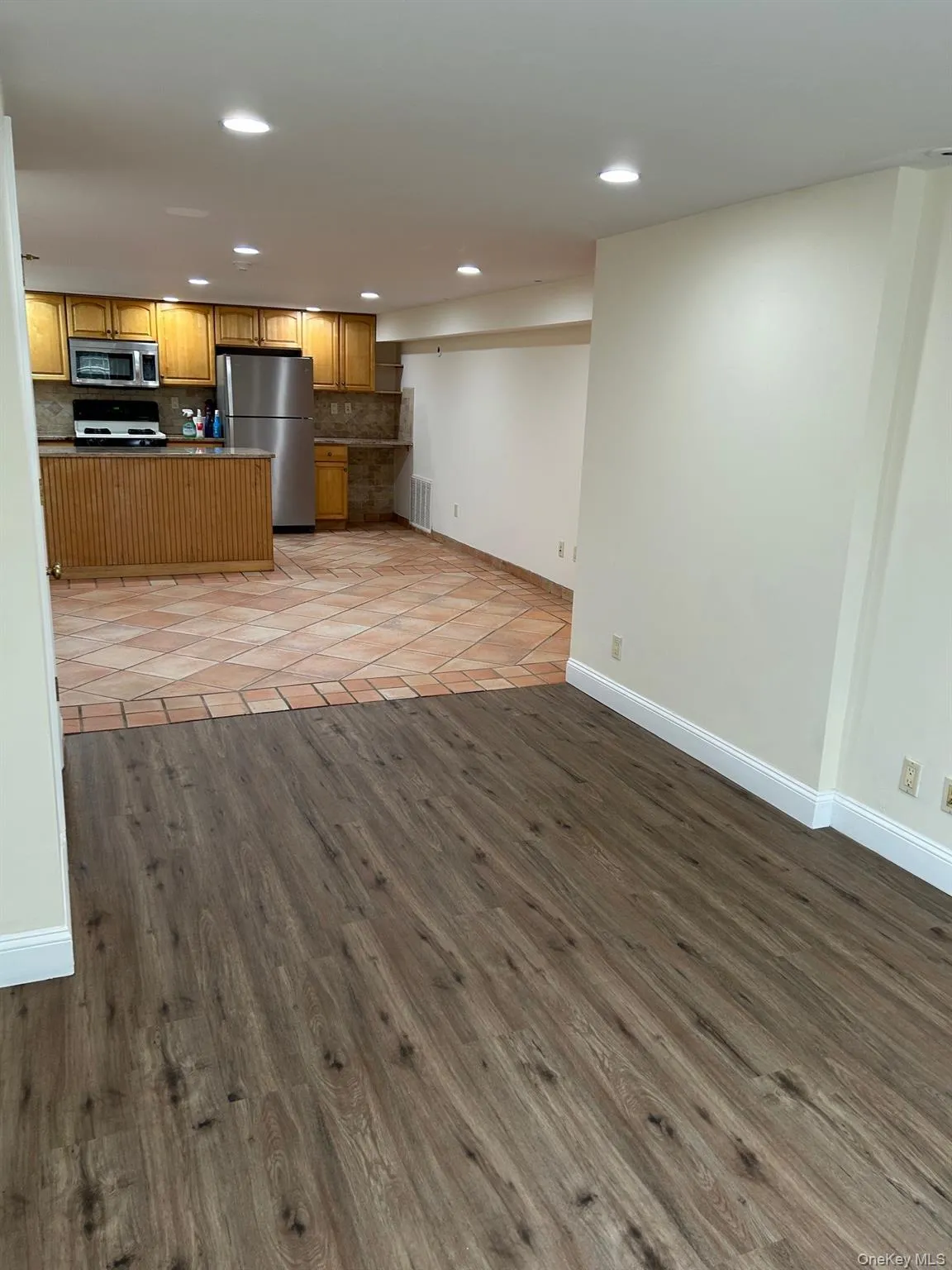 Kitchen featuring open floor plan, stainless steel appliances, brown cabinetry, light wood finished floors, and recessed lighting Kitchen featuring open floor plan, stainless steel appliances, brown cabinetry, light wood finished floors, and recessed lighting