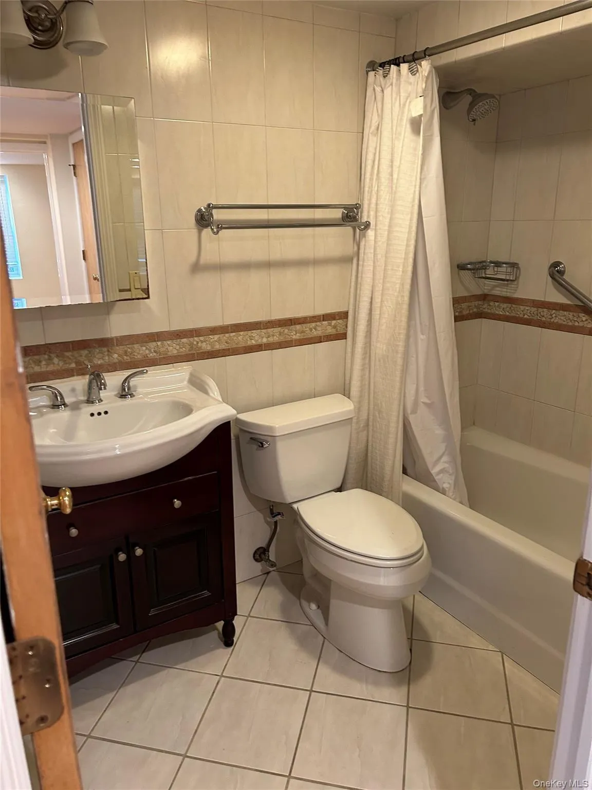 Full bath with vanity, shower / tub combo with curtain, tile walls, and light tile patterned floors Full bath with vanity, shower / tub combo with curtain, tile walls, and light tile patterned floors